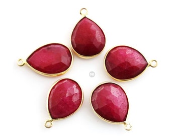 May include: Five teardrop-shaped red gemstone pendants with gold-toned metal settings. The gemstones are faceted and have a shiny finish.
