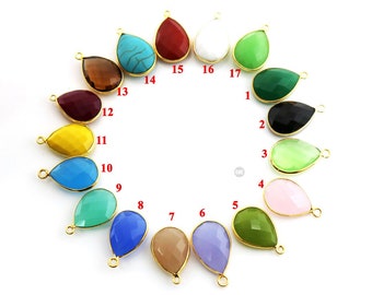 May include: Assortment of 17 teardrop-shaped gemstone pendants with gold-toned accents. The pendants are arranged in a circle and numbered 1 through 17. The gemstones are in various colors, including red, white, green, black, yellow, blue, and pink.