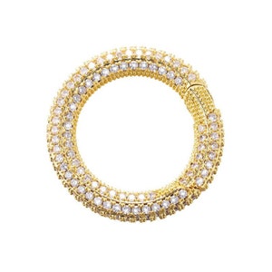 May include: A gold ring with a triple row of clear cubic zirconia stones.