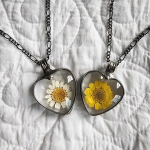 Handmade Daisy Heart Pendant Necklace next to Handmade Sunflower Heart Pendant Necklace on an old quilt. Truly Hand Made in USA by Louisiana Artisan at Bayou Glass Arts Studio. Glass not resin which can scratch and yellow with age.