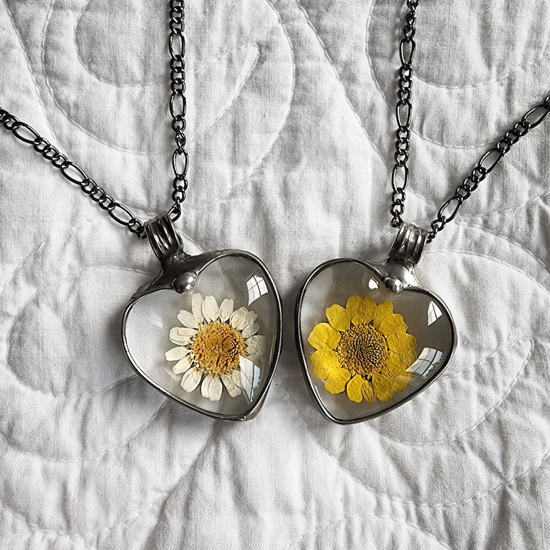Handmade Daisy Heart Pendant Necklace next to Handmade Sunflower Heart Pendant Necklace on an old quilt. Truly Hand Made in USA by Louisiana Artisan at Bayou Glass Arts Studio. Glass not resin which can scratch and yellow with age.