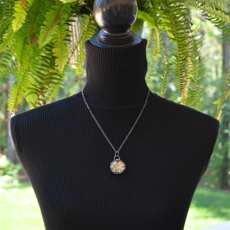 Model wearing Queen Annes Lace Pendant Handmade by Louisiana Artisans at Bayou Glass Arts in USA. White Real Dry Pressed Flower under glass encased with gunmetal/shiny black/aged silver setting. Best gift for Christmas Anniversary Birthday Wedding