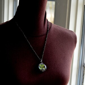 Model wearing Four Leaf Clover Pendant Necklace. Good Luck Charm. Terrarium pendant handmade by Artisans at Bayou Glass Arts. Best gift for March Birthday, wife, mother, girlfriend, Christmas, anniversary, St Patricks Day