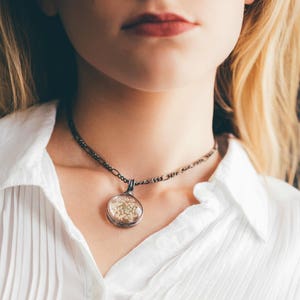 Model wearing Queen Annes Lace Pendant Handmade by Louisiana Artisans at Bayou Glass Arts in USA. White Real Dry Pressed Flower under glass encased with gunmetal/shiny black/aged silver setting. Best gift for Christmas Anniversary Birthday Wedding