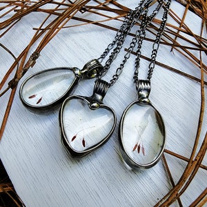 Handmade Dandelion Seed Heart Necklace between the pear shaped dandelion pendant and the oval 3 seed necklace.Created by Artisans at Bayou Glass Arts. Shown with 2 seeds crossed inside Heart shaped Glass Cabochons. Best gift for mom