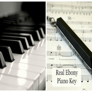 May include: Black and white image featuring a piano keyboard and a real ebony piano key. The key is rectangular with silver-colored metal edges and is resting on sheet music. The text "Real Ebony Piano Key" is also visible.