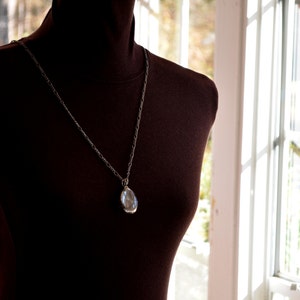 Model shown wearing 24 inch length fully adjustable figaro chain with Dandelion Oval Pendant.