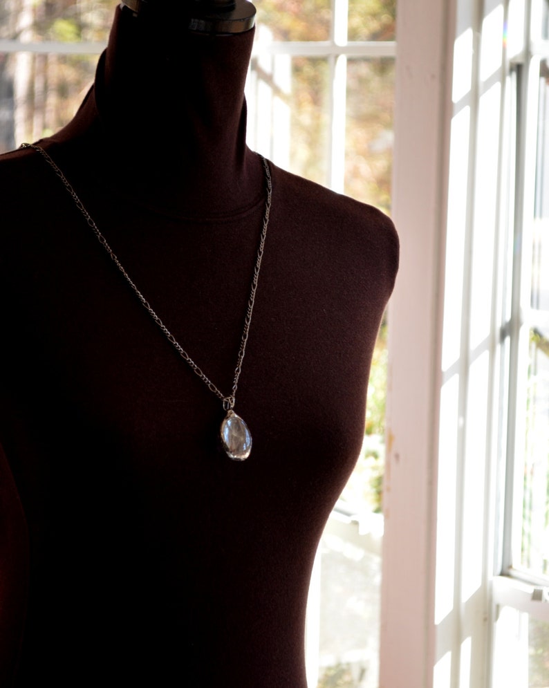 Model shown wearing 24 inch length fully adjustable figaro chain with Dandelion Oval Pendant.