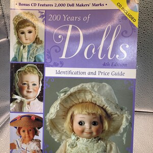 May include: A book titled "200 Years of Dolls" with the subtitle "Identification and Price Guide." The cover features images of antique dolls and the text "CD Included." The book is the 4th edition and is by Dawn Herlocher.