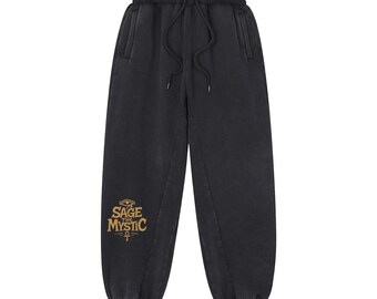 May include: Black sweatpants with a drawstring waist and pockets. The pants feature the text "SAGE MYSTIC" in gold lettering with an eye and ankh symbol. The sweatpants have a relaxed fit and are made of a soft material.