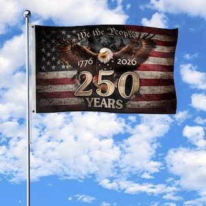 Peut inclure: Un drapeau avec un motif de drapeau américain vieilli, représentant un aigle chauve aux ailes déployées. Le drapeau comprend le texte "We the People", "1776", "2026" et "250 YEARS".