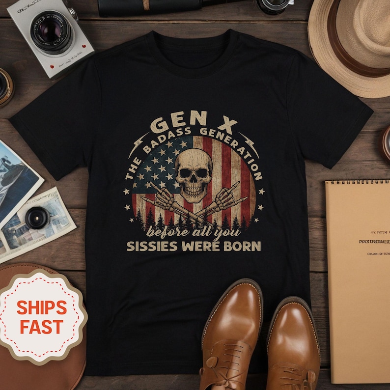 Peut inclure: T-shirt noir avec un motif graphique repr&eacute;sentant un cr&acirc;ne, des mains de squelette et le texte "GEN X The Badass Generation before all you Sissies Were Born" sur un motif de drapeau am&eacute;ricain.