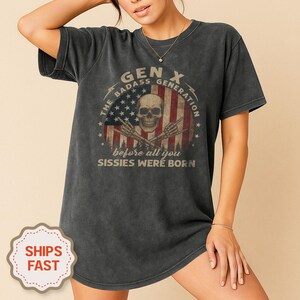 Peut inclure: Robe t-shirt gris fonc&eacute; avec un motif vieilli d'un cr&acirc;ne, du drapeau am&eacute;ricain et le texte "GEN X THE BADASS GENERATION before all you Sissies were born". Le t-shirt a un aspect vintage et us&eacute;.