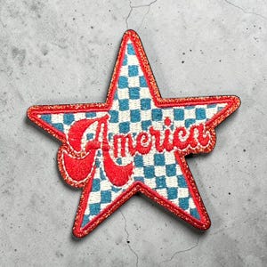 May include: A white ceramic mug with a black handle and the text "But First, Coffee" in a bold, black font. The mug is set against a blurred background, suggesting a cozy setting.