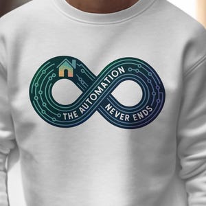 May include: White sweatshirt featuring a teal and blue infinity symbol design with a house icon and the text "THE AUTOMATION NEVER ENDS." The design is centered on the chest. The sweatshirt is made of a soft material.