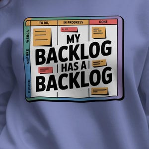 May include: A periwinkle blue sweatshirt with a graphic on the front that reads "MY BACKLOG HAS A BACKLOG." The graphic is designed to look like a project management board with the words "TO DO," "IN PROGRESS," and "DONE."