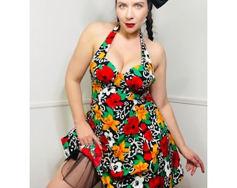 May include: A woman wearing a black and white halter dress with a floral print. The dress has a sweetheart neckline and a fitted bodice. The woman is wearing a black bow in her hair.