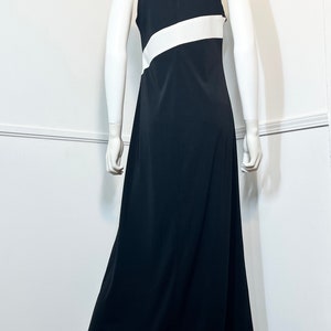 May include: A black maxi dress with a white stripe across the chest. The dress has a halter neckline and a sleeveless design.