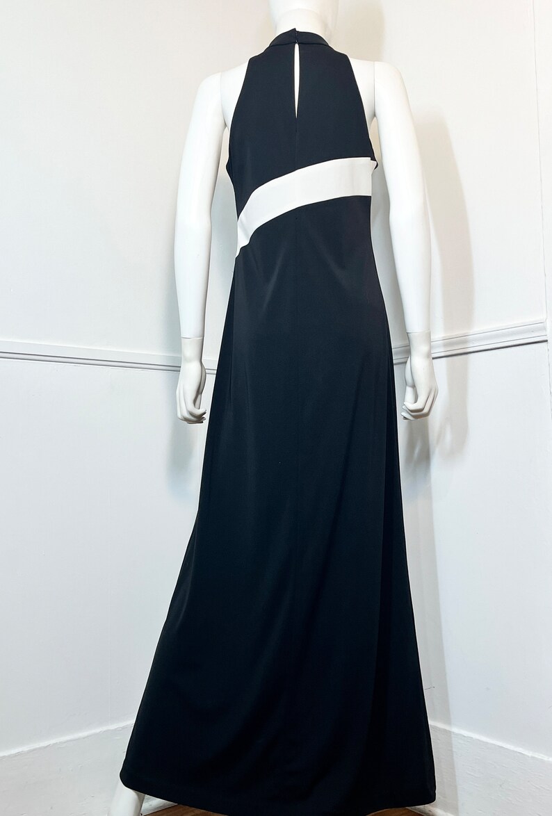 May include: A black maxi dress with a white stripe across the chest. The dress has a halter neckline and a sleeveless design.
