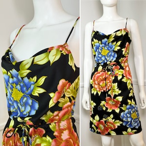 Puede incluir: Un vestido negro sin mangas con cuello de pico y estampado floral. El vestido tiene una cintura con cordón y una longitud corta.