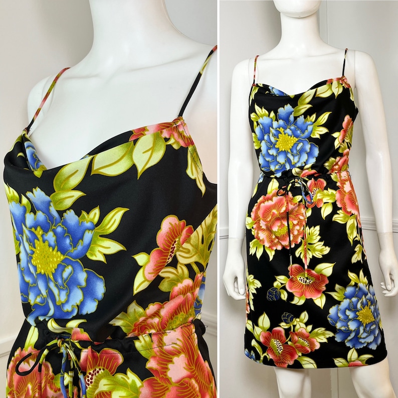 May include: A black sleeveless dress with a cowl neck and floral print. The dress has a drawstring waist and a short length.