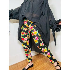 May include: Black sheer top with long sleeves and a floral print pair of pants. The top has a loose fit and the pants are skinny fit.