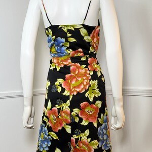 May include: A black sleeveless dress with a floral print featuring large red, pink, blue, and green flowers. The dress has a scoop neck and a fitted silhouette.