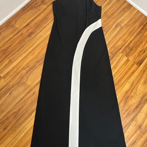 May include: A black maxi dress with a white stripe down the side. The dress has a halter neckline and a fitted silhouette.