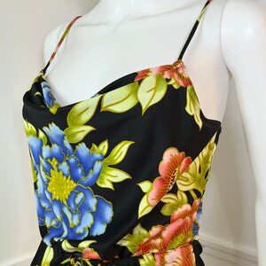 May include: A black floral print dress with a cowl neck and thin straps. The dress has a drawstring waist and a large floral print in shades of blue, pink, green, and yellow.