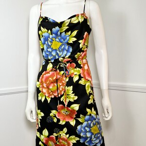 May include: A black sleeveless dress with a floral print featuring large pink, blue, and yellow flowers. The dress has a cowl neck and a drawstring waist.