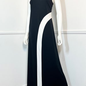 May include: A black maxi dress with a white curved design on the side. The dress has a high neck and sleeveless design.