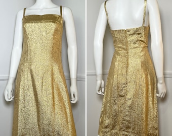 May include: A gold sleeveless dress with a sparkly, textured fabric. The dress has a straight, fitted silhouette and a simple, elegant design.