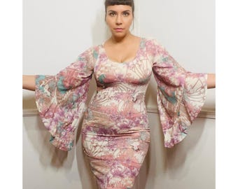 May include: A long-sleeved dress with a floral print in shades of pink, white, and blue. The dress has a fitted bodice and a flowing skirt. The sleeves are wide and bell-shaped.