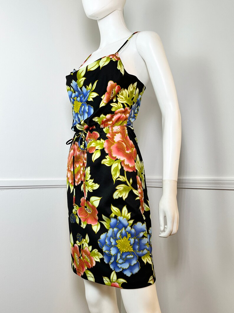 May include: A black floral print dress with a scoop neck and thin straps. The dress has a drawstring waist and a fitted silhouette.