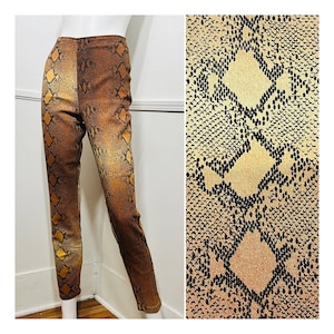 Może przedstawiać: Brązowe i beżowe spodnie wężowe z wysokim stanem. Spodnie mają dopasowany krój i są wykonane z elastycznego materiału.