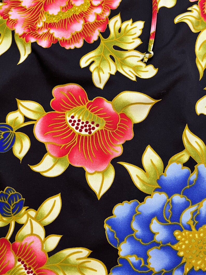May include: Black fabric with a floral pattern featuring pink, red, blue, and gold flowers. The flowers are stylized and have a traditional Japanese design.