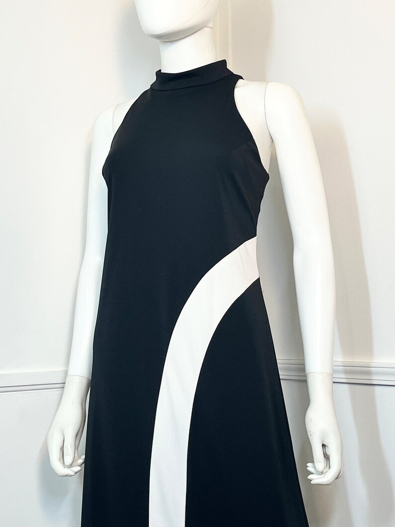 May include: A black sleeveless maxi dress with a white curved design on the side.