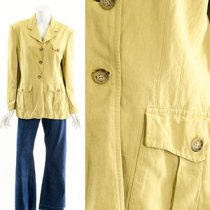 May include: A light yellow blazer with four buttons and two front pockets. The blazer is paired with dark blue denim jeans. The blazer has a classic design with a notched collar and buttoned cuffs. The buttons are a light brown color.