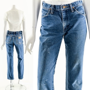Puede incluir: Un par de pantalones vaqueros azules de mezclilla con corte recto. Los vaqueros tienen un lavado claro y est&aacute;n desgastados con decoloraci&oacute;n y marcas de desgaste. Los vaqueros tienen un estilo cl&aacute;sico de cinco bolsillos con cierre de bot&oacute;n.