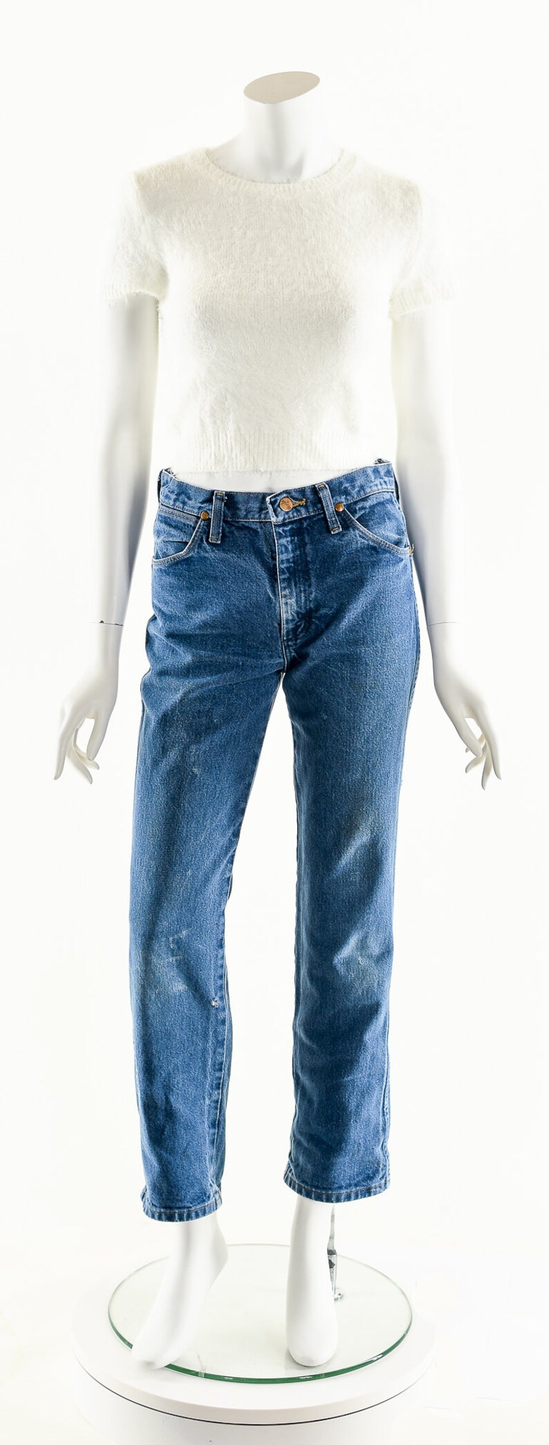 Puede incluir: Un su&eacute;ter blanco de manga corta peludo y pantalones vaqueros azules de mezclilla en un maniqu&iacute; blanco.