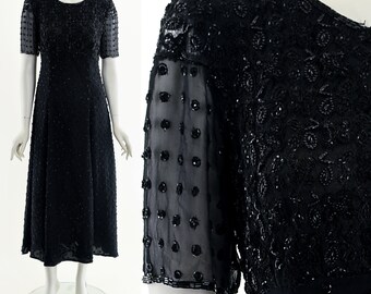 May include: A black beaded dress with a round neckline and short sleeves. The dress is made of a sheer fabric with sequins and beads.