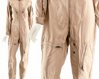 May include: A tan flight suit with multiple pockets and a zipper closure. The suit has a collared neckline and long sleeves.