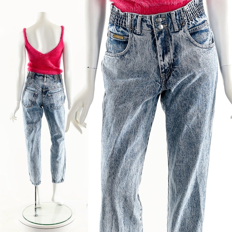 May include: Light blue acid wash denim jeans with a high waist and a relaxed fit. The jeans have a faded look and a slightly distressed appearance.