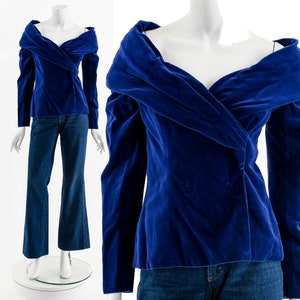 May include: A royal blue velvet off-the-shoulder top with long sleeves and a draped neckline.