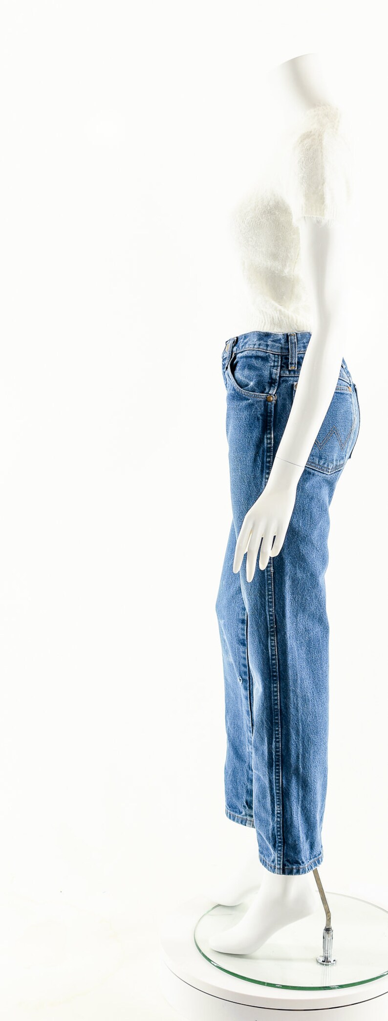 Puede incluir: Un top blanco peludo de corte corto y unos vaqueros azules de mezclilla en un maniqu&iacute; blanco.
