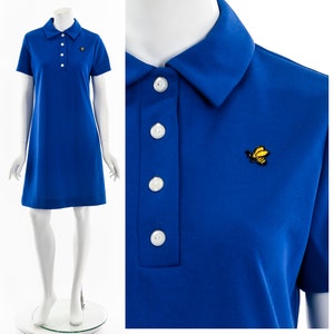 Peut inclure: Une robe bleu royal à manches courtes avec un col et une petite abeille jaune brodée sur la poitrine. La robe a un devant boutonné.