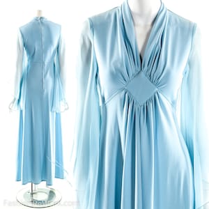 Op de afbeelding: Een lichtblauwe maxi-jurk met lange, wijde mouwen en een V-hals. De jurk heeft een aansluitend bovenlijf en een zwierige rok.