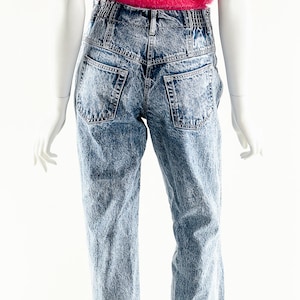 May include: A pink fuzzy cropped tank top paired with light blue acid wash denim jeans.