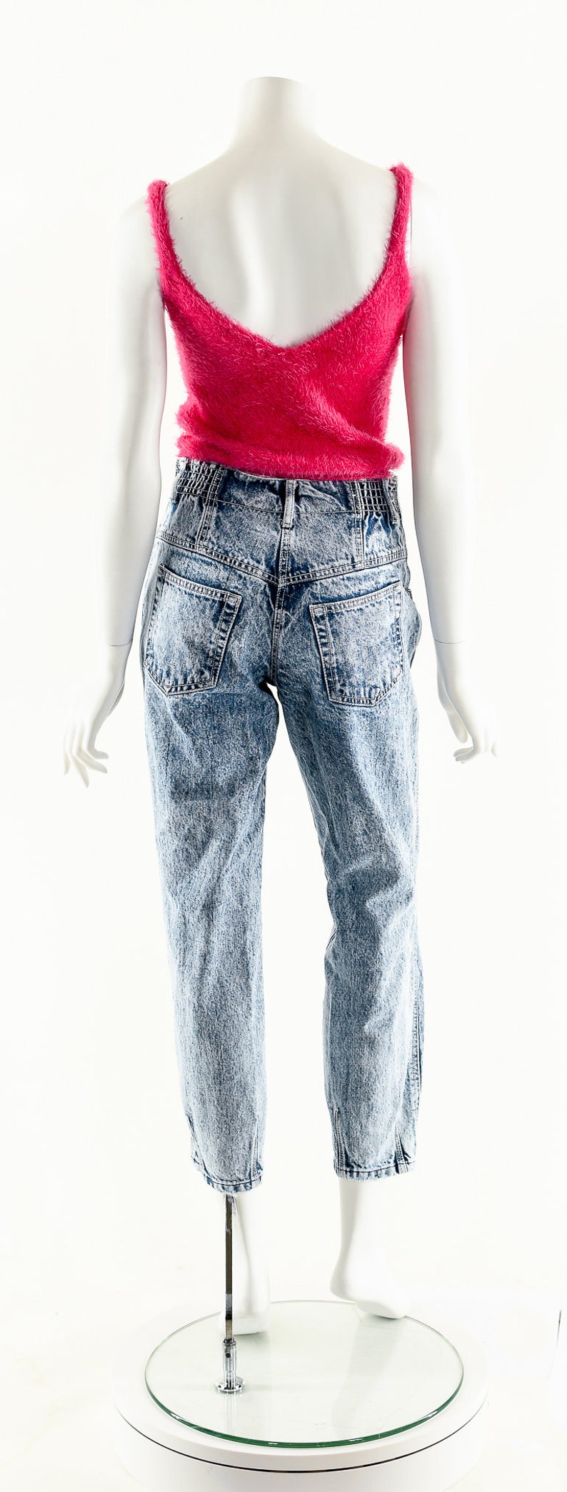 May include: A pink fuzzy cropped tank top paired with light blue acid wash denim jeans.