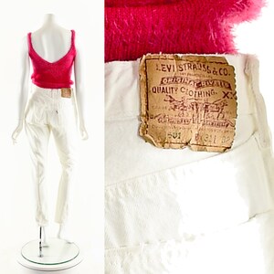 May include: White high-waisted jeans with a Levi's patch on the back pocket. The patch reads "Levi Strauss & Co. Original riveted quality clothing XX".